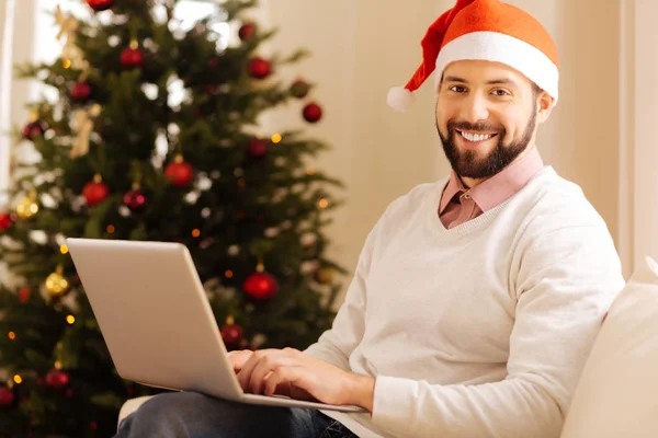 Charmant homme en chapeau Santa posant avec ordinateur portable — Photo