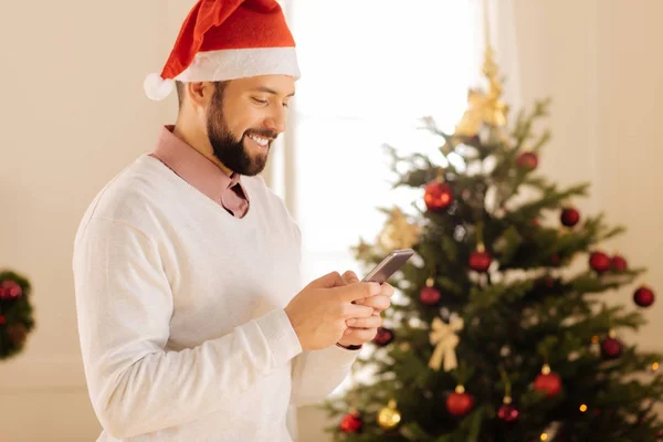 Vrolijke man in Santa hat texting met vrienden — Stockfoto