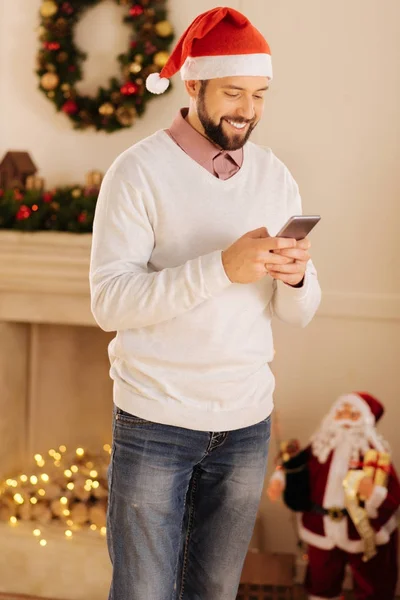 Joyeux homme dans le chapeau de Père Noël lire des messages texte — Photo