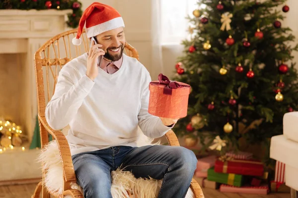Улыбающийся мужчина разговаривает по телефону и держит подарочную коробку — стоковое фото