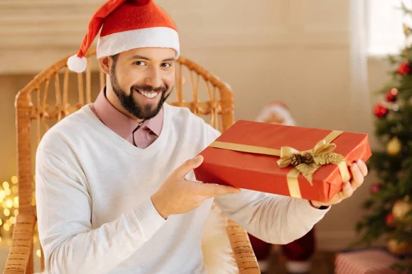 Homme heureux dans le chapeau de Père Noël posant avec boîte cadeau — Photo