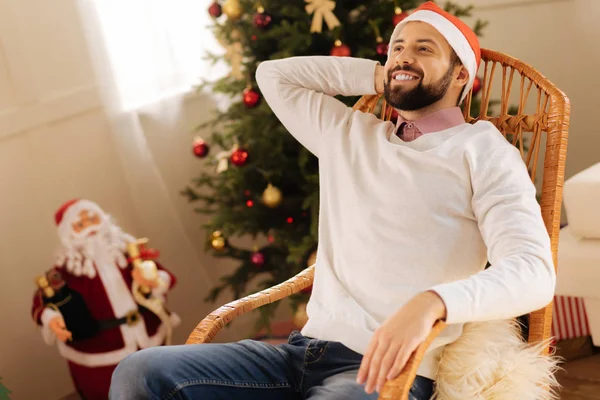 Noel Baba şapkası sallanan sandalyede rahatlatıcı yakışıklı adam