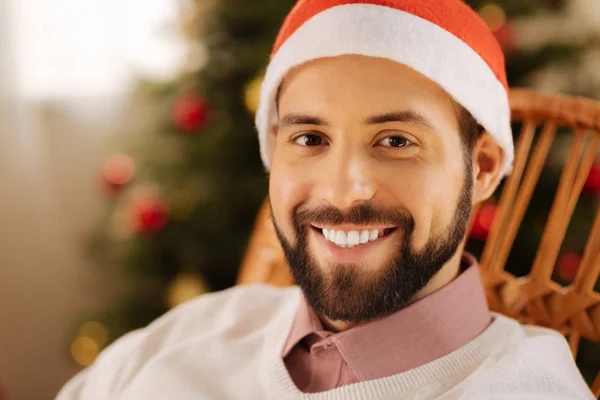 Glücklicher Mann mit Weihnachtsmütze posiert im Schaukelstuhl — Stockfoto