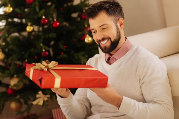 Mosolygó ember nézi piros ajándék doboz — Stock Fotó
