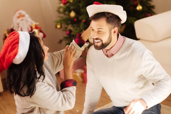 Loving wife putting Santa hat on her husband — Stock Photo, Image