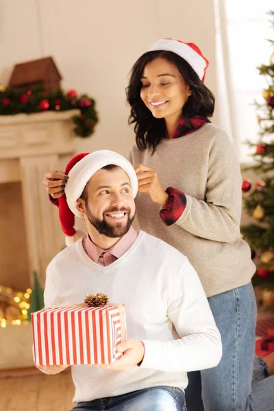 Αγαπώντας γυναίκα προσαρμογή Santa καπέλο στο κεφάλι της συζύγους — Φωτογραφία Αρχείου