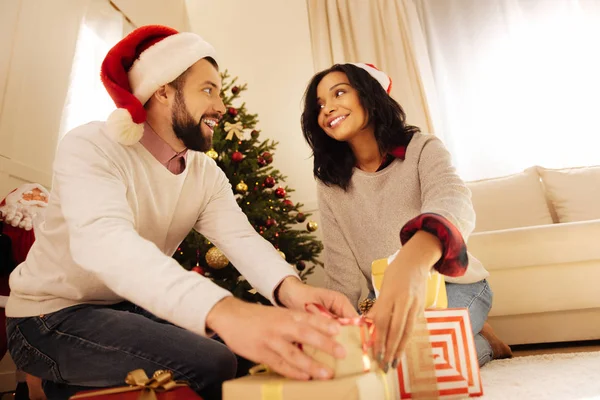Lächelnder Mann hilft seiner Frau, Geschenke unter den Weihnachtsbaum zu legen — Stockfoto