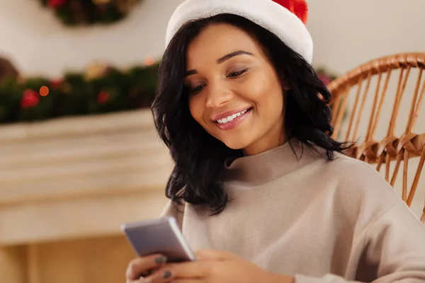 Lachende vrouw in KERSTMUTS om tekstberichten te verzenden — Stockfoto