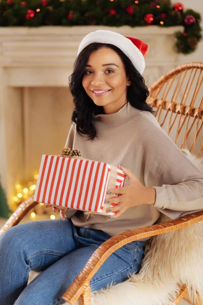 Mujer encantadora posando en mecedora con regalo de Navidad — Foto de Stock