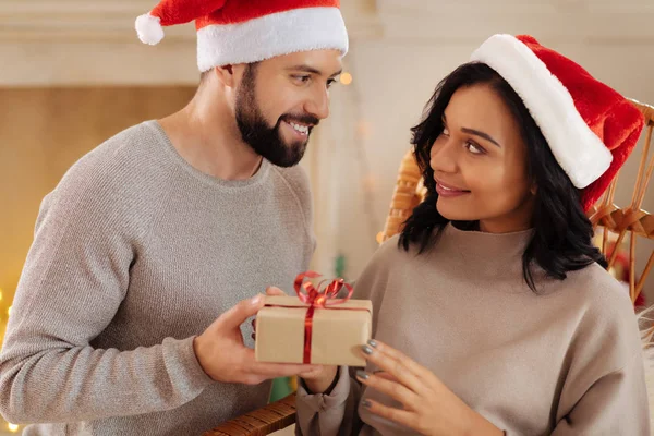 Sorrindo homem em chapéu de Santa dando presente de Natal à esposa — Fotografia de Stock
