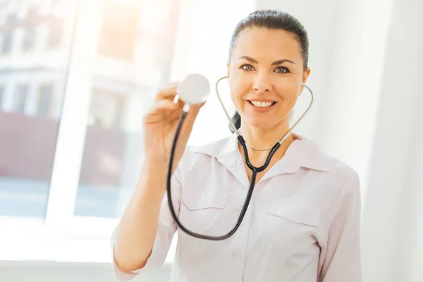 Enthusiastic millennial brunette posing with stethoscope for camera — Stock Photo, Image