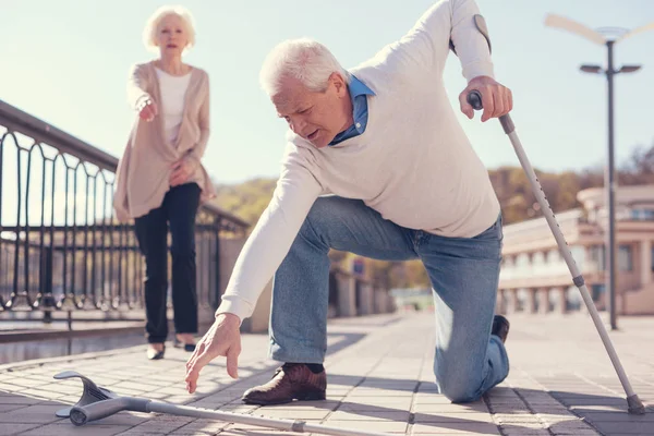 Senior man picking up his fallen crutch — Stock Photo, Image