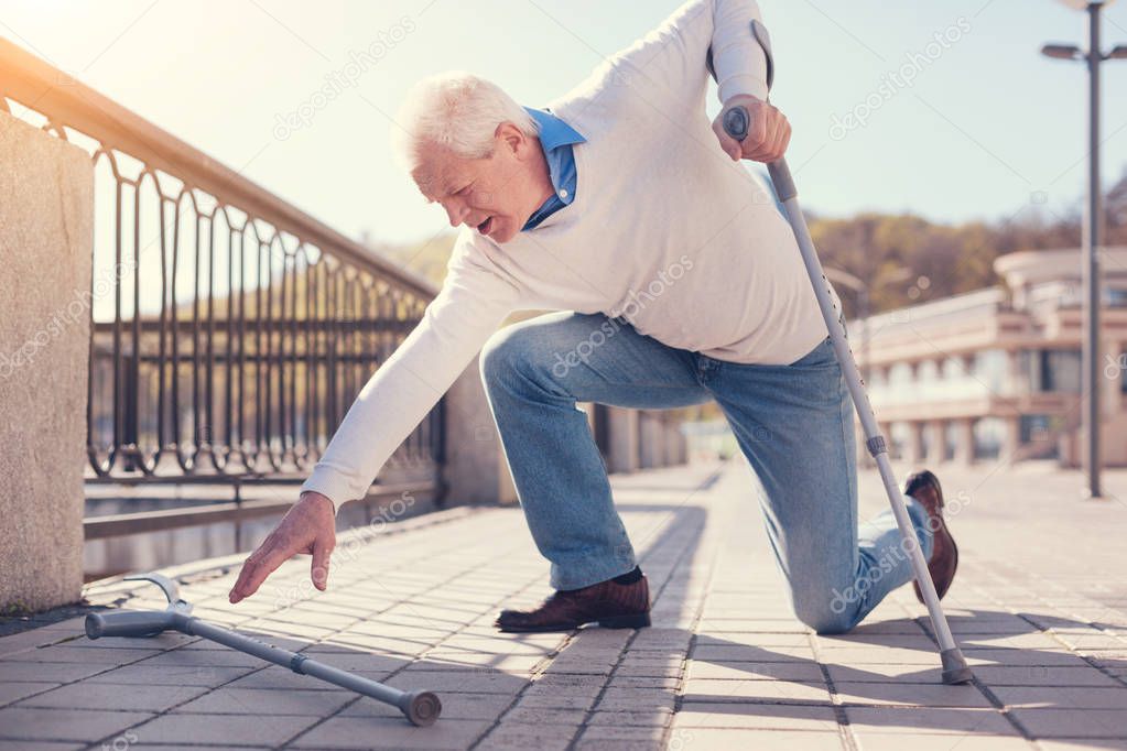 Elderly man reaching for crutch 