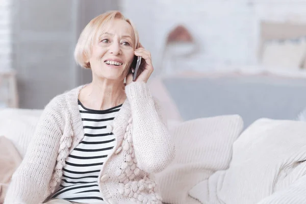 Сияющая старшая леди разговаривает по телефону дома — стоковое фото