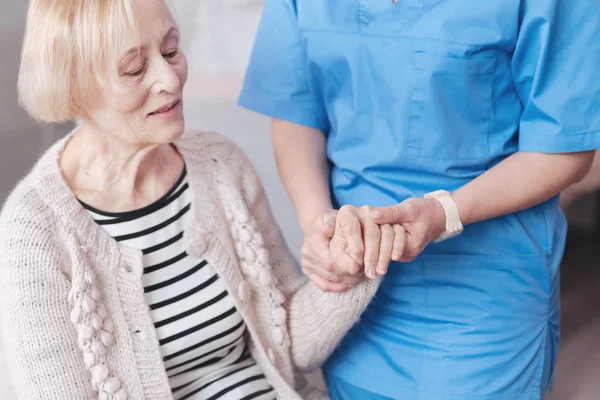 Gros plan d'une infirmière réfléchie tenant la main d'un patient âgé — Photo