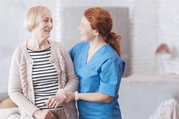 Amichevole infermiera e paziente anziano femminile guardando l'un l'altro — Foto Stock