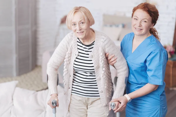 Cuidadosa doctora ayudando a su anciano paciente a caminar — Foto de Stock
