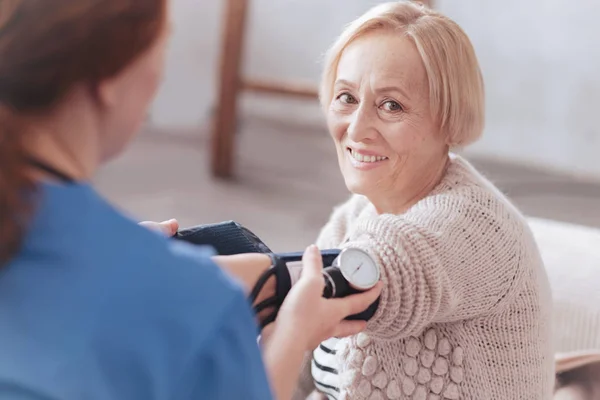 Felice signora in pensione sorridente mentre controlla la pressione sanguigna — Foto Stock