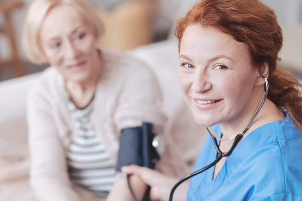 Radiant médecin féminin avec sphygmomanomètre souriant dans la caméra — Photo