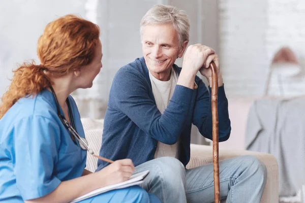 Веселый пожилой пациент разговаривает с медицинским работником — стоковое фото