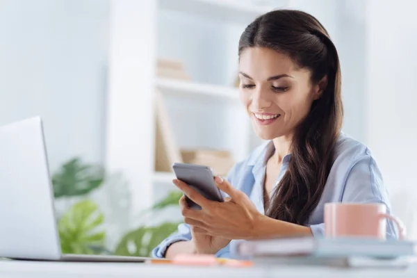 Mujer autónoma positiva usando su teléfono inteligente — Foto de Stock