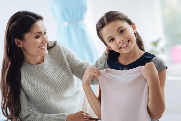 Delighted cute girl holding a new dress — Stock Photo, Image