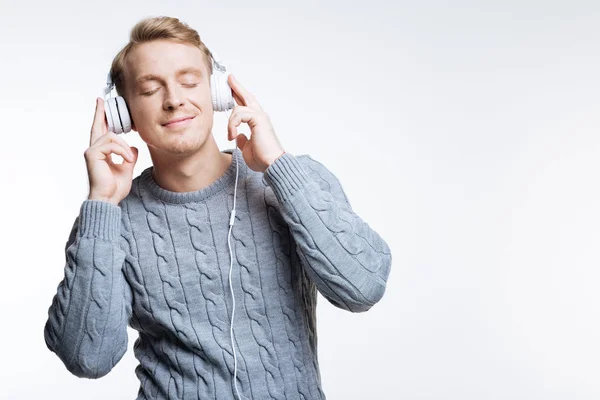 Blonder junger Mann, der über Kopfhörer Musik hört — Stockfoto