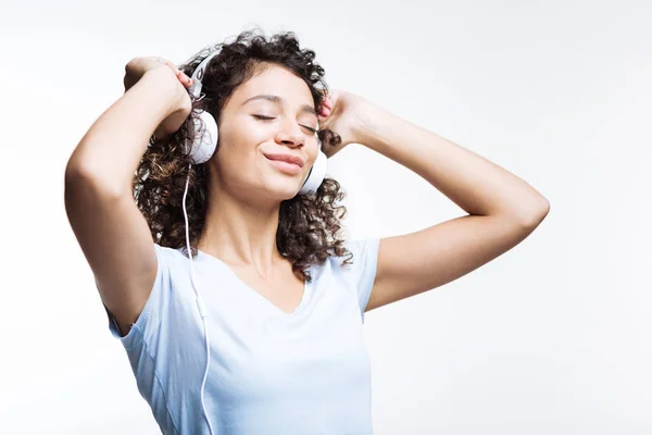 Mulher de cabelos encaracolados ouvindo música em fones de ouvido — Fotografia de Stock