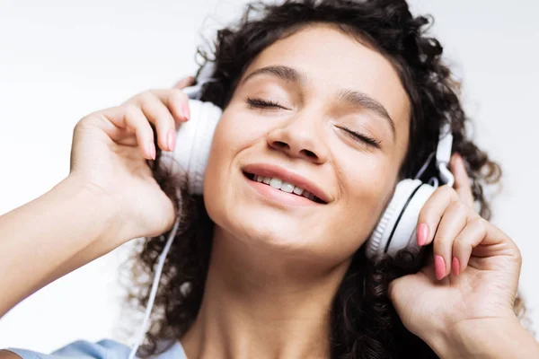 Happy woman closing eyes while listening to music — Stock Photo, Image