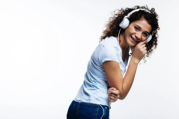 Przyjemna kobieta kręconych włosach, śmiech podczas słuchania muzyki — Zdjęcie stockowe