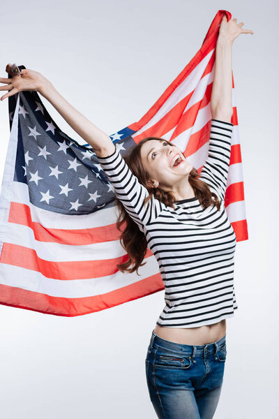 Slim cheerful woman lifting up US flag behind her back