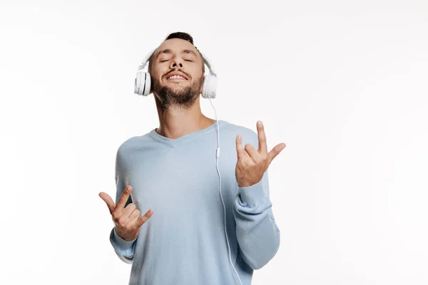Bristled homem ouvindo música e mostrando sinal de chifres — Fotografia de Stock