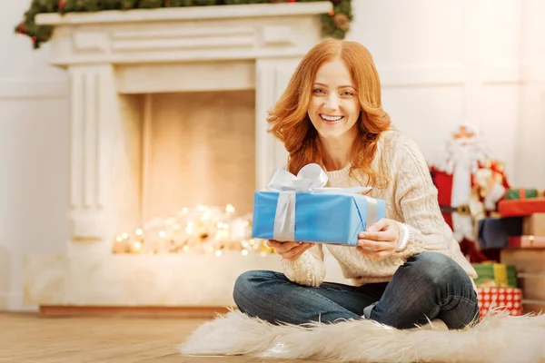 Радостная женщина с рождественским подарком улыбается в камеру — стоковое фото