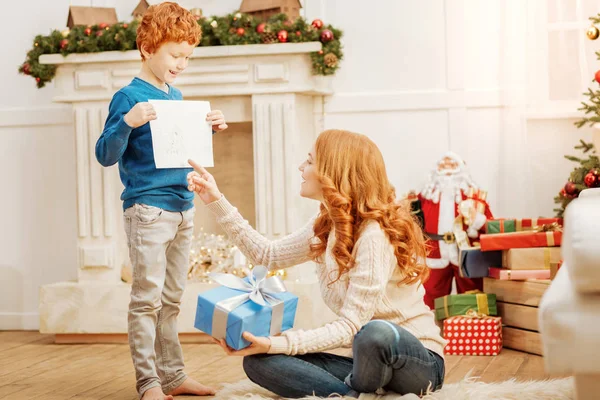 Loving ginger kid showing his mother new drawing — Stock Photo, Image