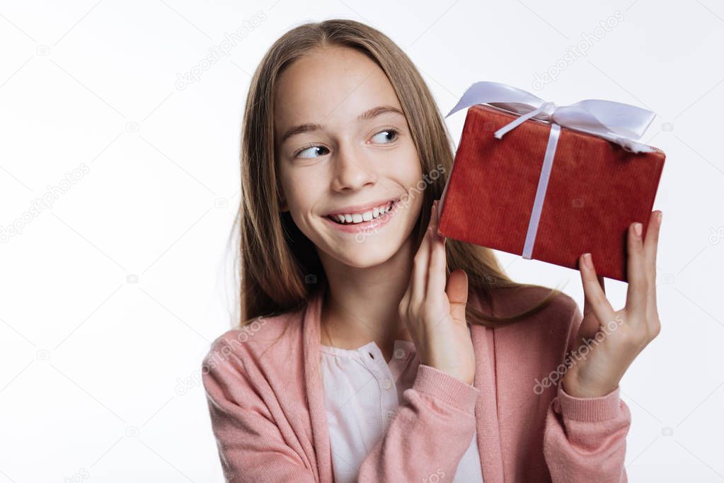 Adorable teenage girl looking at box with present