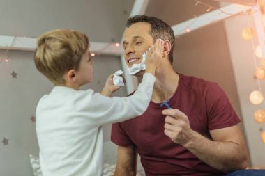 Neşeli çocuk köpük babasının yüzüne koydu