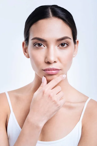 Portrait of dark-haired young woman touching her chin — Stock Photo, Image