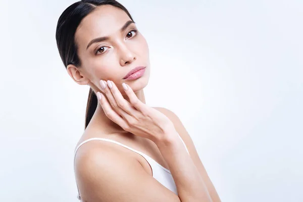 Beautiful young woman touching her cheek while posing — Stock Photo, Image