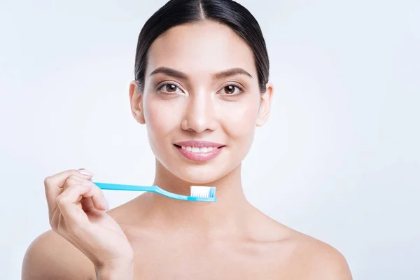 Приємна усміхнена жінка тримає зубну щітку горизонтально — стокове фото