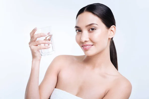 Hermosa joven sosteniendo un vaso de agua y sonriendo — Foto de Stock