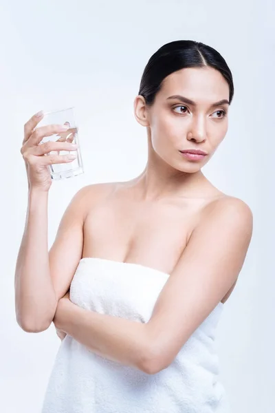 Ładna Brunetka w ręcznik, trzymając szklankę wody — Zdjęcie stockowe