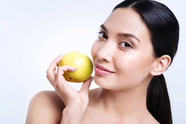 Aangename dark-haired vrouw met apple in de buurt van haar gezicht — Stockfoto