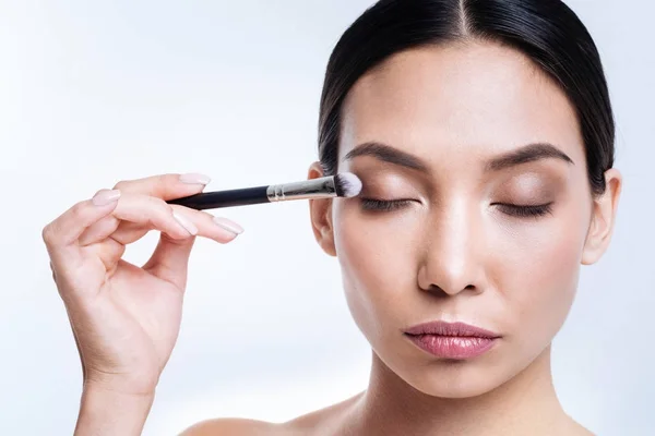 Charming woman applying eye shadows with brush — Stock Photo, Image