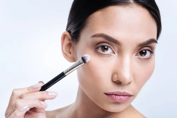 Close up of beautiful woman holding makeup brush near face — Stock Photo, Image