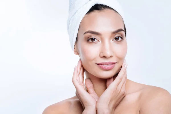 Pleasant woman in a towel turban touching face with hands — Stock Photo, Image