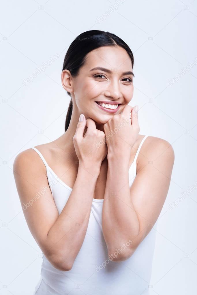 Happy young woman laughing while posing against white background