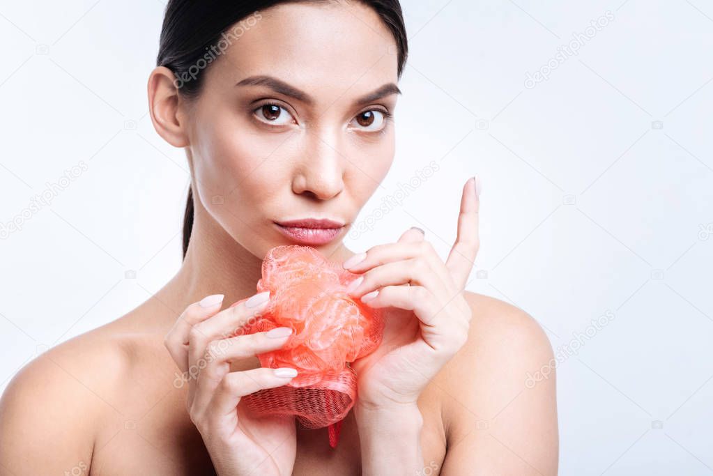 Charming woman holding coral bath sponge