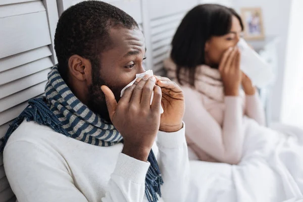 Two ill people sneezing while sitting together — Stock Photo, Image