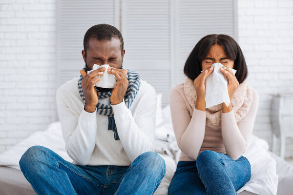 Cute young people sneezing simultaneously