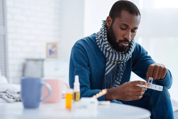 Hombre serio y tranquilo tomando una píldora de una caja de pastillas — Foto de Stock